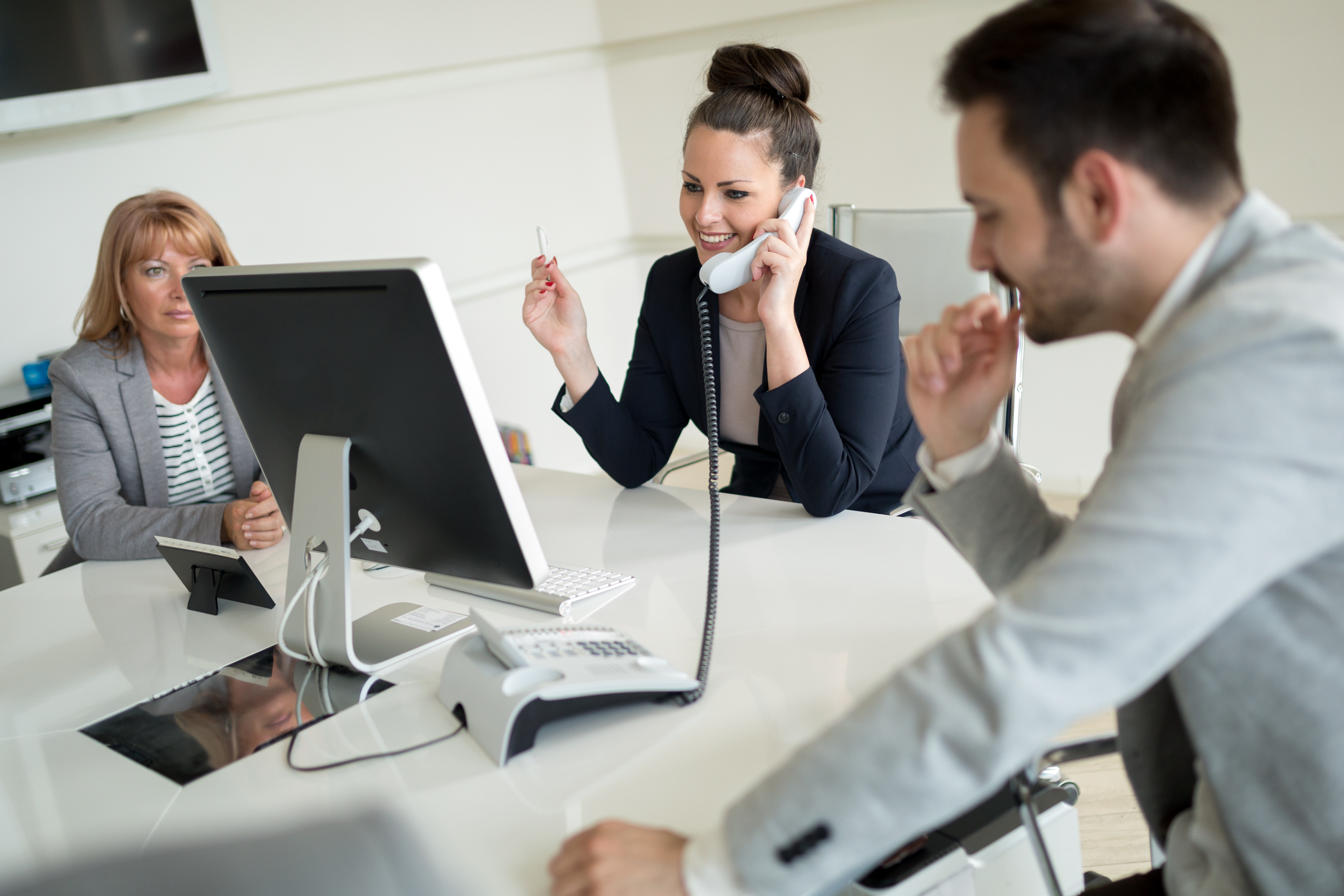 two businesswomen and a man working together around a table